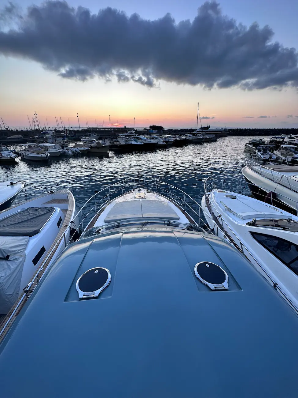 Yachts moored at the marina at sunset, with golden sky over the Bay of Naples